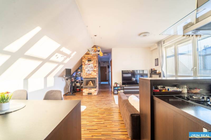 Nappali egy kétszobás lakásban fa dekor padlóval és téglakandallóval.