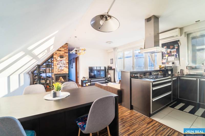 Konyha televízióval, kandallóval és fa hatású padlóval egy kétszobás lakásban.