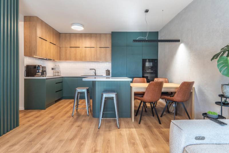 Konyha egy háromszobás lakásban fa dekor padlóval és étkezőasztallal.