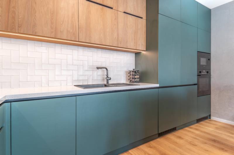 Konyha türkiz szekrényekkel, fa dekorációval és fehér csempékkel, 3 szobás lakás.