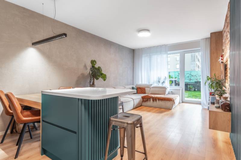 Nappali egy háromszobás lakásban kényelmes kanapéval és fa dekorációjú padlóval.