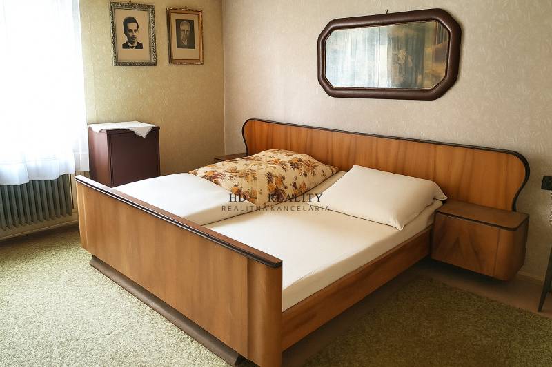 Hálószoba fa ággyal, fényképekkel a falon és tükörrel egy családi házban.