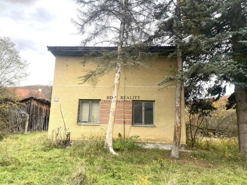 Családi ház Rykynčice-ben, fákkal körülvéve, lejtős telekkel és fa melléképülettel.