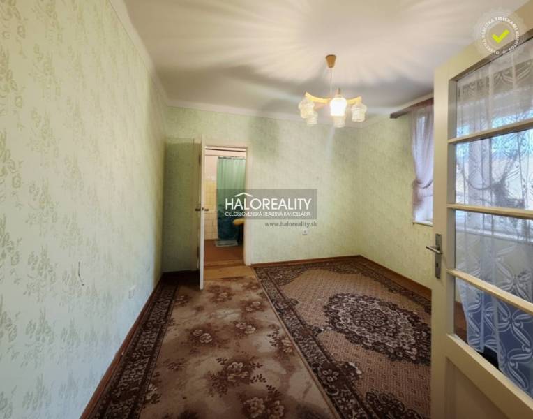 Szoba egy családi házban szőnyeggel, zöld falakkal és dekoratív világítással.