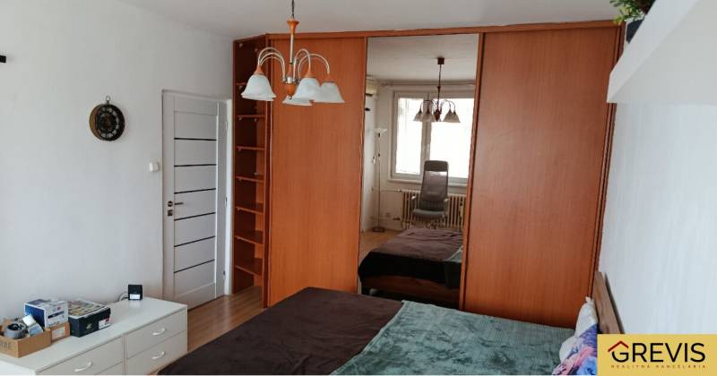 Hálószoba egy egyszobás lakásban nagy tükrös szekrénnyel és csillárral.