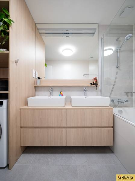 Fürdőszoba egy háromszobás lakásban két mosdóval, tükörrel és káddal.