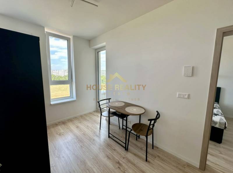 Étkező sarok egy kétszobás lakásban fa mintázatú padlóval és nagy ablakokkal.