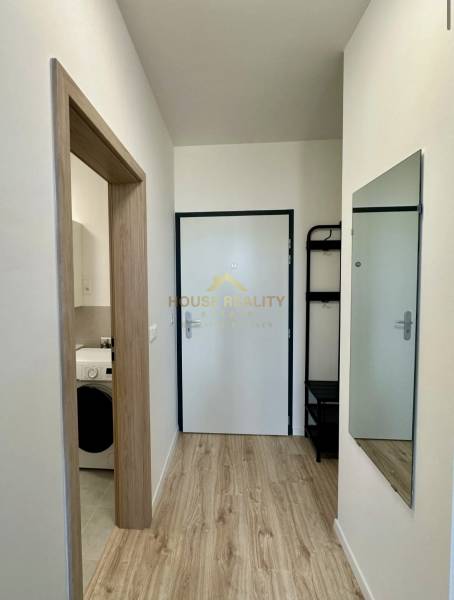 Folyosó fa mintás padlóval, tükörrel és fürdőszobai bejárattal egy kétszobás lakásban.