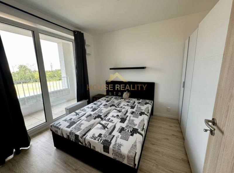 Hálószoba egy kétszobás lakásban, ággyal, szekrénnyel és erkéllyel, fa dekorációjú padlóval.