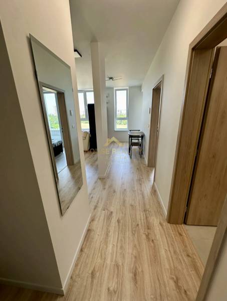 Folyosó egy 2 szobás lakásban, fa mintás padlóval, világos színnel és fali tükörrel.