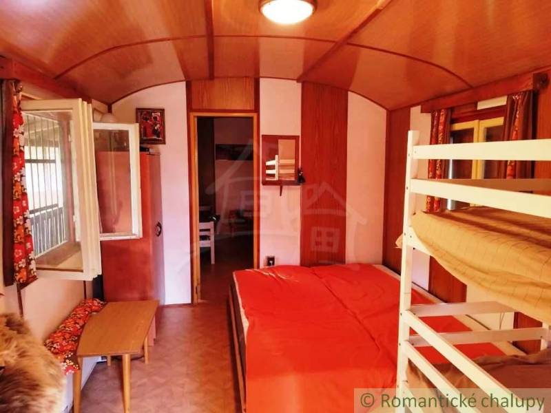 A kunyhó belseje emeletes ággyal, fa dekoros padlóval és nyitott ablakkal.
