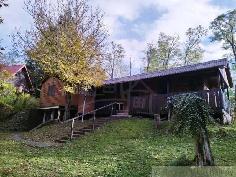 Házikó Dudincon, természet által körülvéve, terasszal és fákkal az udvaron.