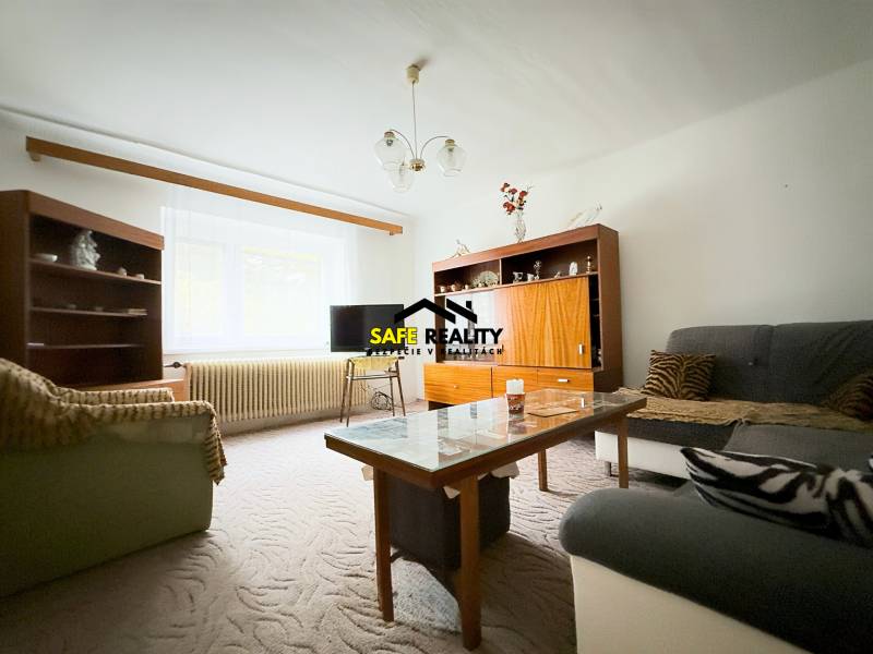 Nappali a családi házban kanapékkal, szekrényekkel és asztallal, szőnyeggel a padlón.