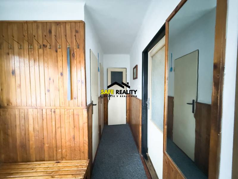 Családi ház előszobája fa burkolattal és tükörrel a falon.