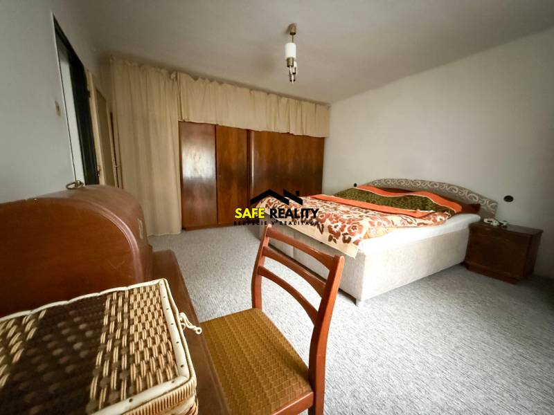 Hálószoba családi házban szőnyeggel, ággyal és szekrénnyel.