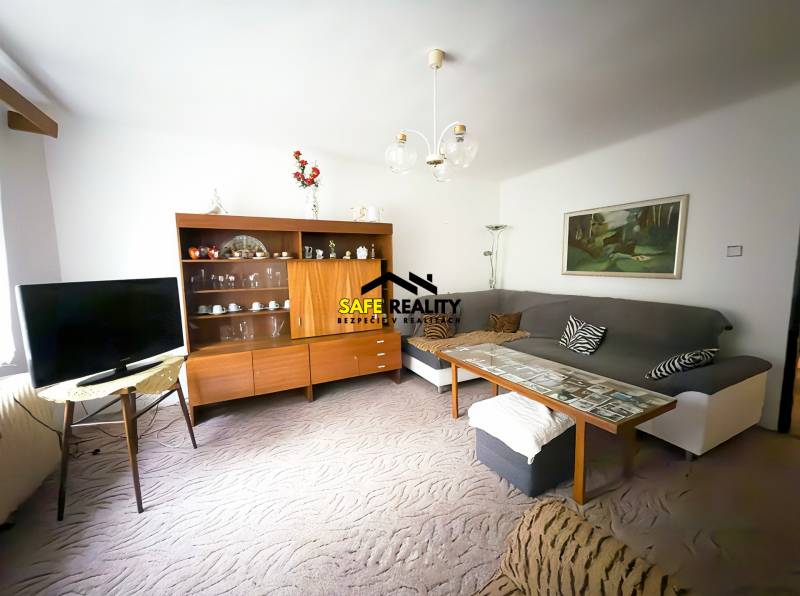 Nappali családi házban kanapéval, televízióval és fa nappali szekrénnyel.