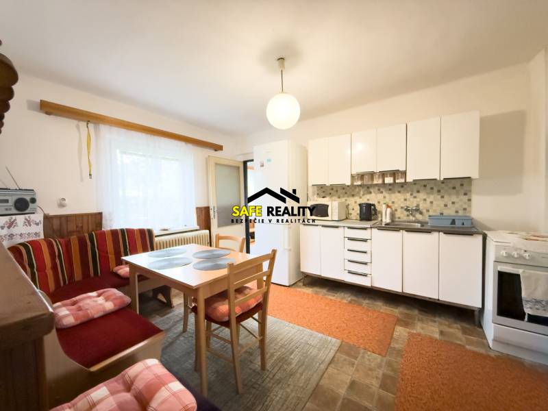 Konyha családi házban világos bútorokkal, étkezőasztallal és ülőhellyel.