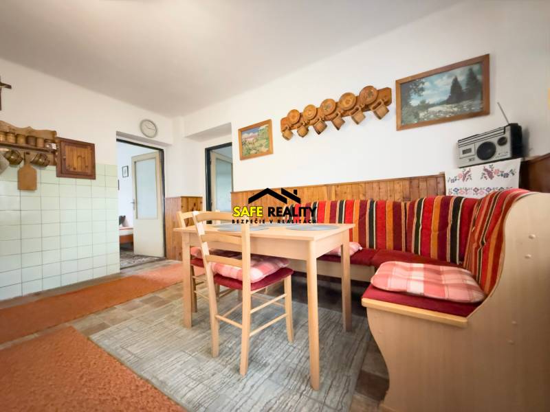 Családi ház étkezője sarokpadokkal, fa dekorációval és dekoratív képekkel a falon.