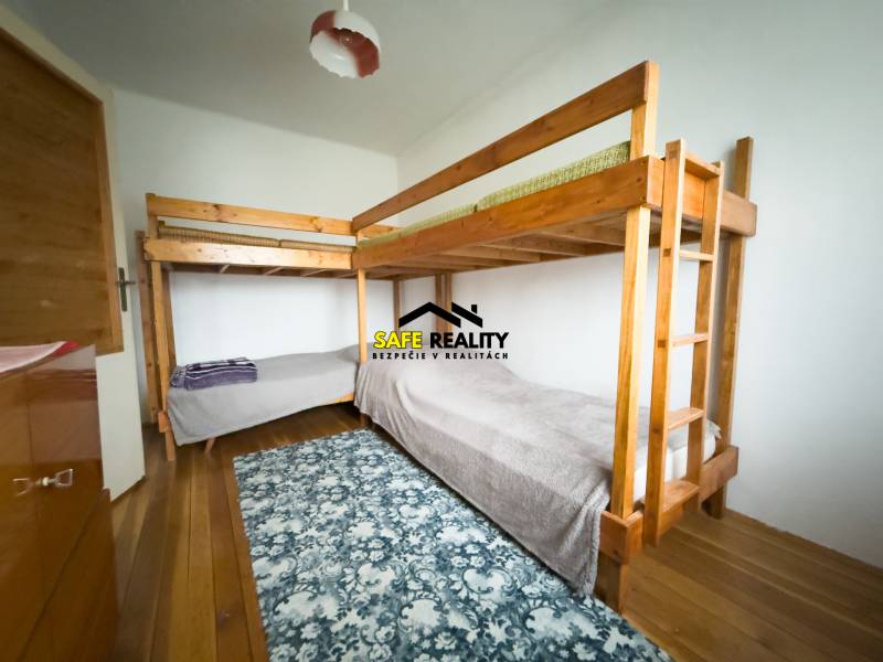 Emeletes ágy egy családi házban, fa mintás padlóval és mintás szőnyeggel.