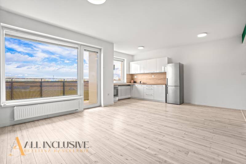 Világos belső tér kétszobás lakásban konyhával, üvegfallal és fa dekorációjú padlóval.