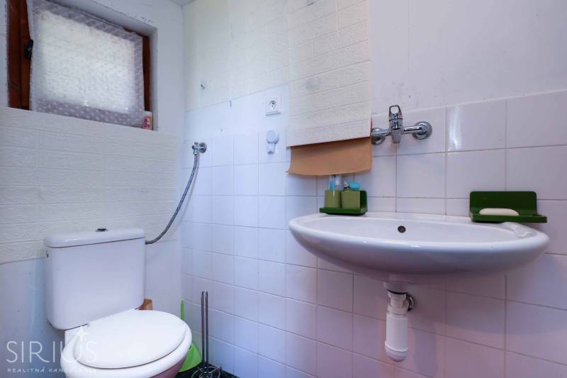 Fürdőszoba zuhanyzóval és mosdóval, Kertek. Fehér csempék és zöld kiegészítők.