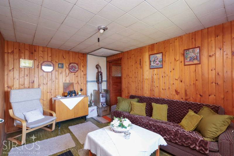 Szoba kanapéval, fotellel, asztallal és faburkolattal hangulatos teret kínál a kertekben.