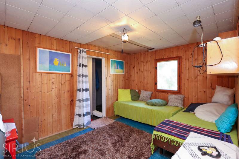 Fa falburkolat, kanapék párnákkal és szőnyeggel a kerti ház belsejében.