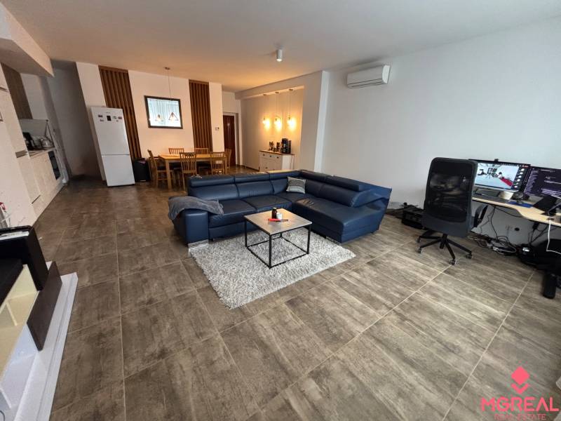 Nappali egy kétszobás lakásban kék kanapéval és íróasztallal.