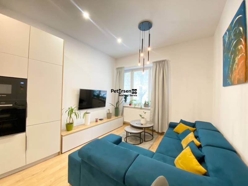 Nappali egy kétszobás lakásban kék kanapéval és fa mintázatú padlóval.