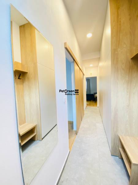 Folyosó fa dekor padlóval egy kétszobás lakásban, szekrényekkel és tükörrel.