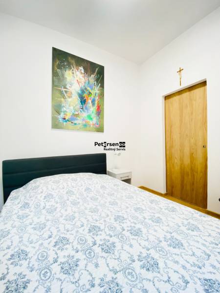 Hálószoba egy képpel a falon, ággyal és éjjeliszekrénnyel egy kétszobás lakásban.