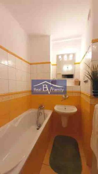 Fürdőszoba egy kétszobás lakásban meleg árnyalatú csempével és káddal.