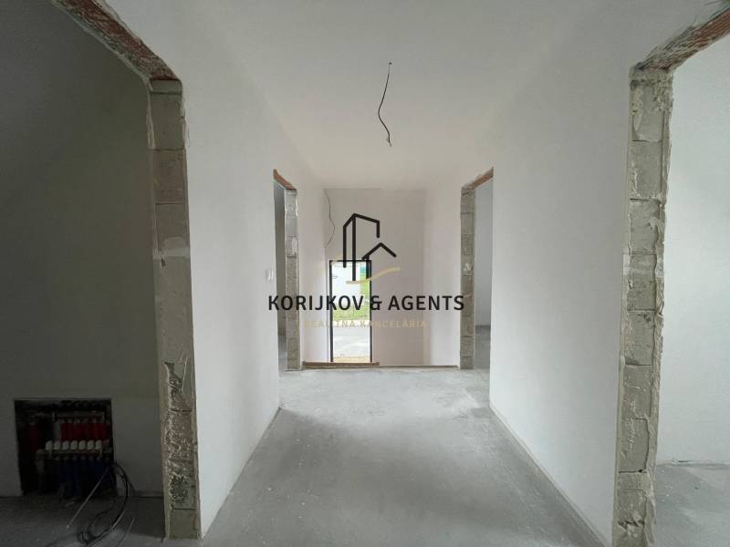 Családi ház belső tere fehér falakkal és nyitott ajtókkal a következő helyiségbe.