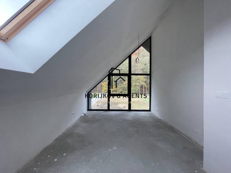 Tetőtéri szoba nagy ablakokkal és kiemelt mennyezettel egy családi házban, padlóburkolat nélkül.