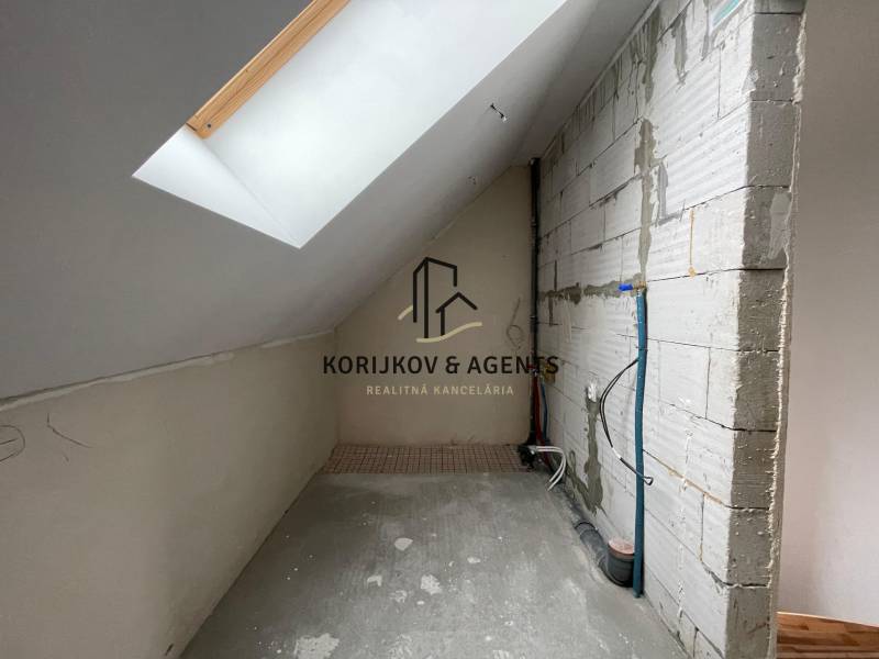 Családi ház tetőtéri helyisége betonpadlóval és tetőablakkal.