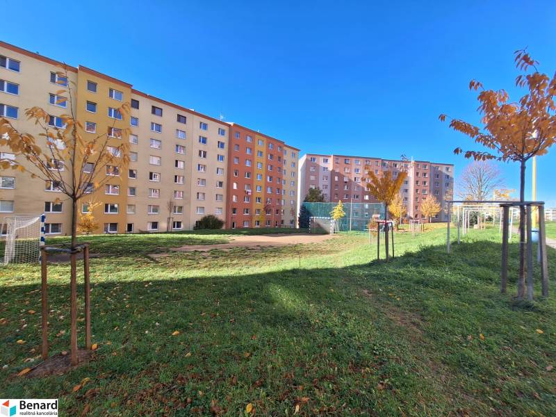 Lakótelepi épületek a Federátov utcában, Eperjesen, játszótérrel és fákkal.