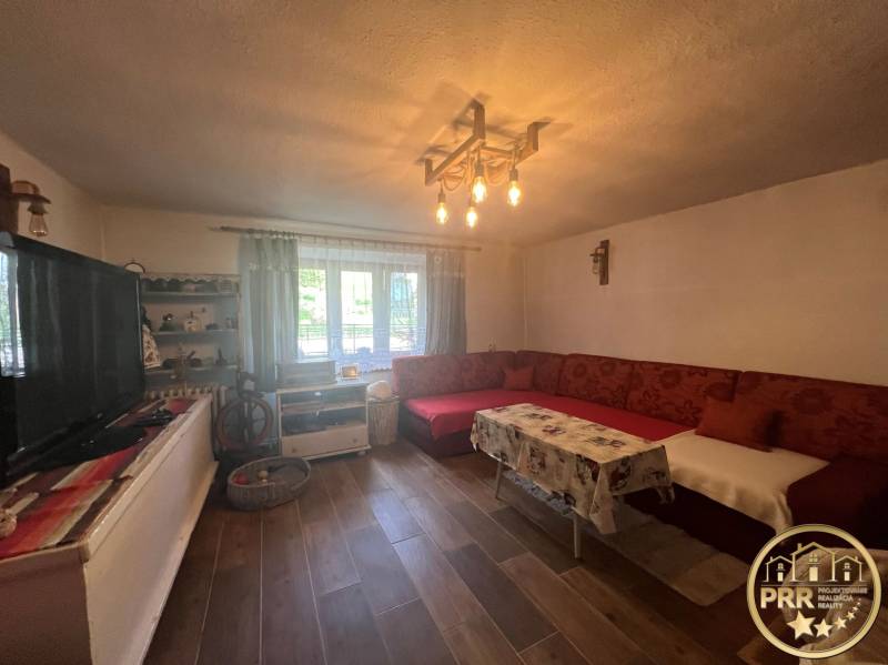 Nappali és faház hagyományos bútorokkal, kanapéval és fa padlóval a pihenéshez.