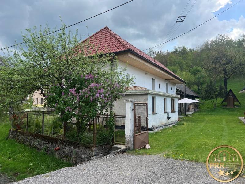 Vidéki ház zölddel körülvéve, rusztikus tetővel, virágzó kerttel és fa pavilonnal.