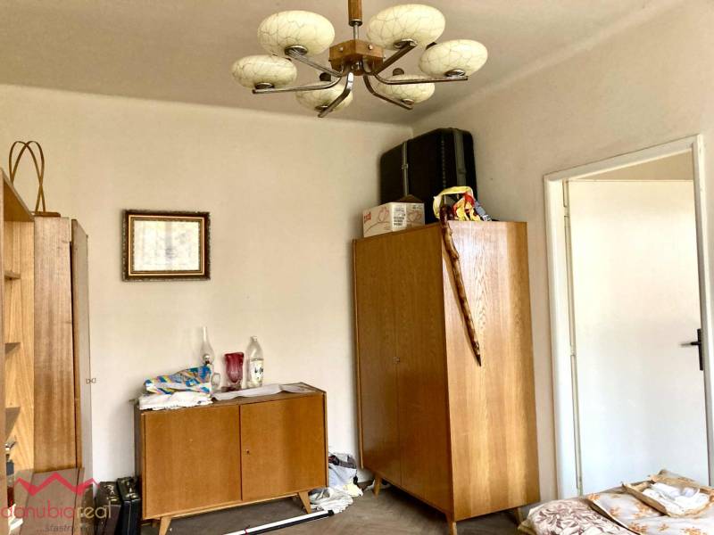 Szoba egy háromszobás lakásban fa bútorokkal és dekoratív csillárral.