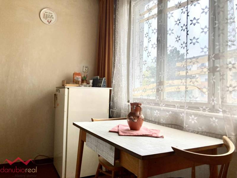 Ebédlő egy háromszobás lakásban asztallal, székekkel és virágmintás függönyökkel.