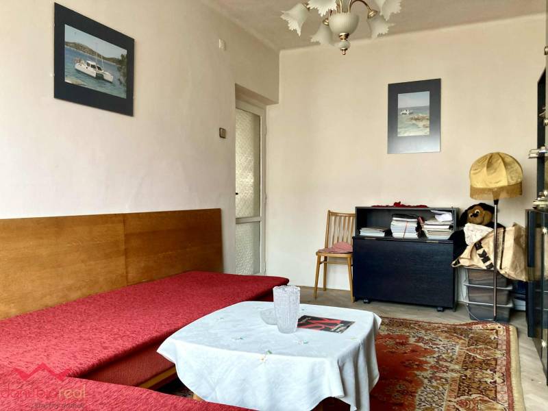 Nappali egy háromszobás lakásban kanapéval, szőnyeggel és dekoratív képekkel a falon.