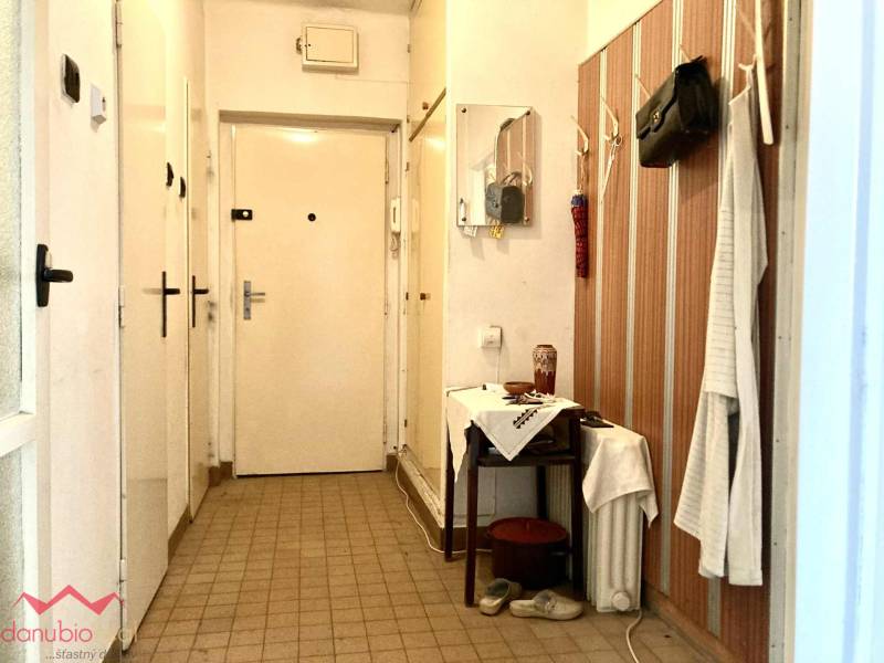 Előszoba egy háromszobás lakásban falra szerelt fogassal és tükörrel.