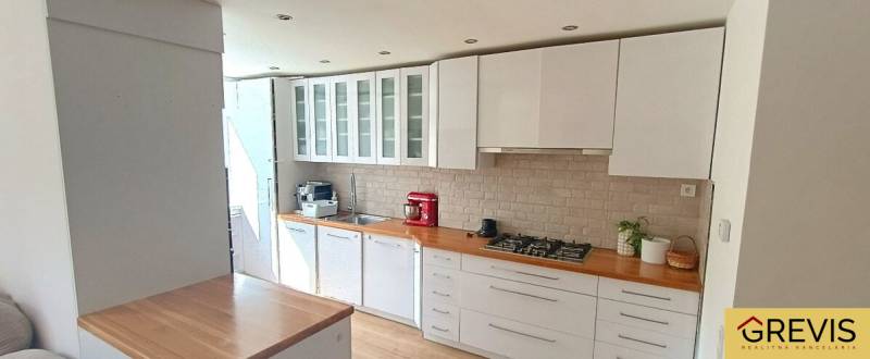 Konyha egy háromszobás lakásban fehér bútorokkal és tűzhellyel, fa dekoros padlóval.