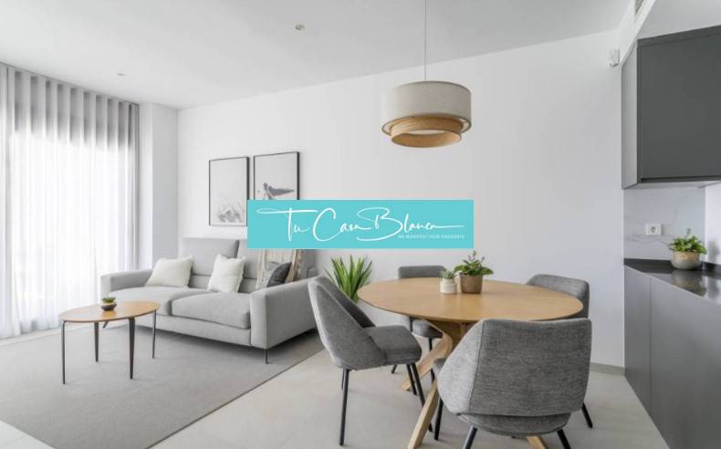 Világos nappali a nyaraló apartmanban szürke fotellel és faasztallal.