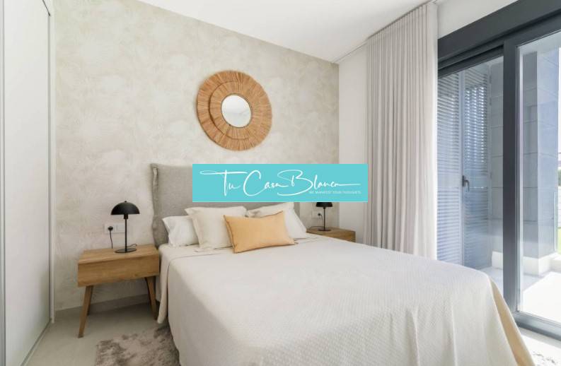 Hálószoba egy üdülő apartmanban, ágy, éjjeliszekrények, nagy ablak.