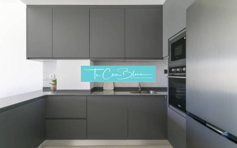 Konyha a nyaraló apartmanban sötét szekrényekkel és beépített készülékekkel.