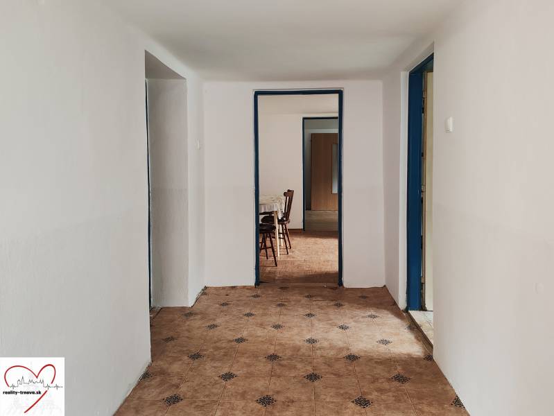 Egy családi ház folyosója csempével és bútorokkal a háttérben.