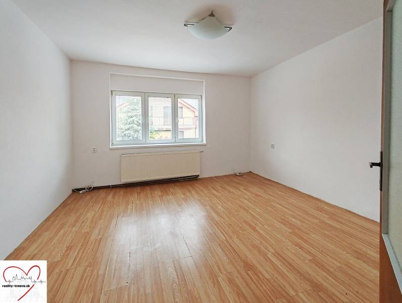 Egy családi ház szobája fa mintázatú padlóval és nagy ablakkal.