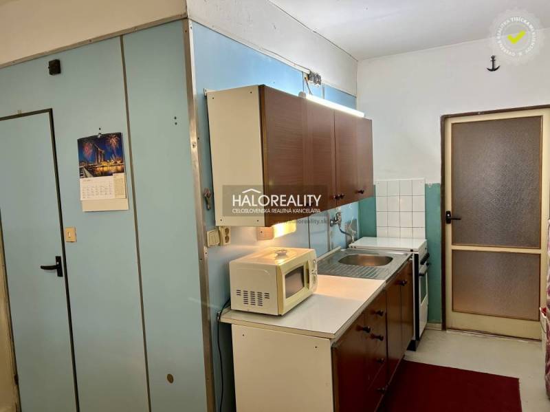 Konyha fa szekrényekkel és fehér készülékekkel egy négyszobás lakásban.