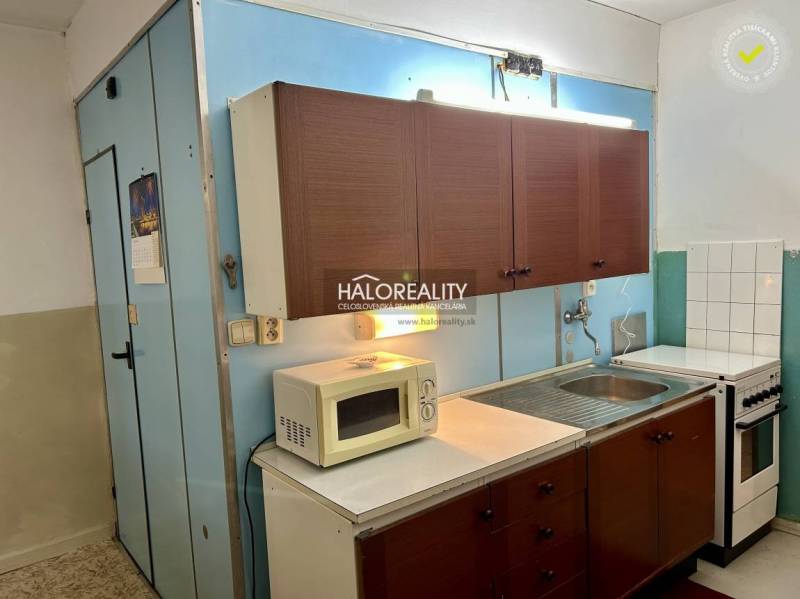 Konyha régebbi szekrényekkel, mikrohullámú sütővel és tűzhellyel egy 4 szobás lakásban.